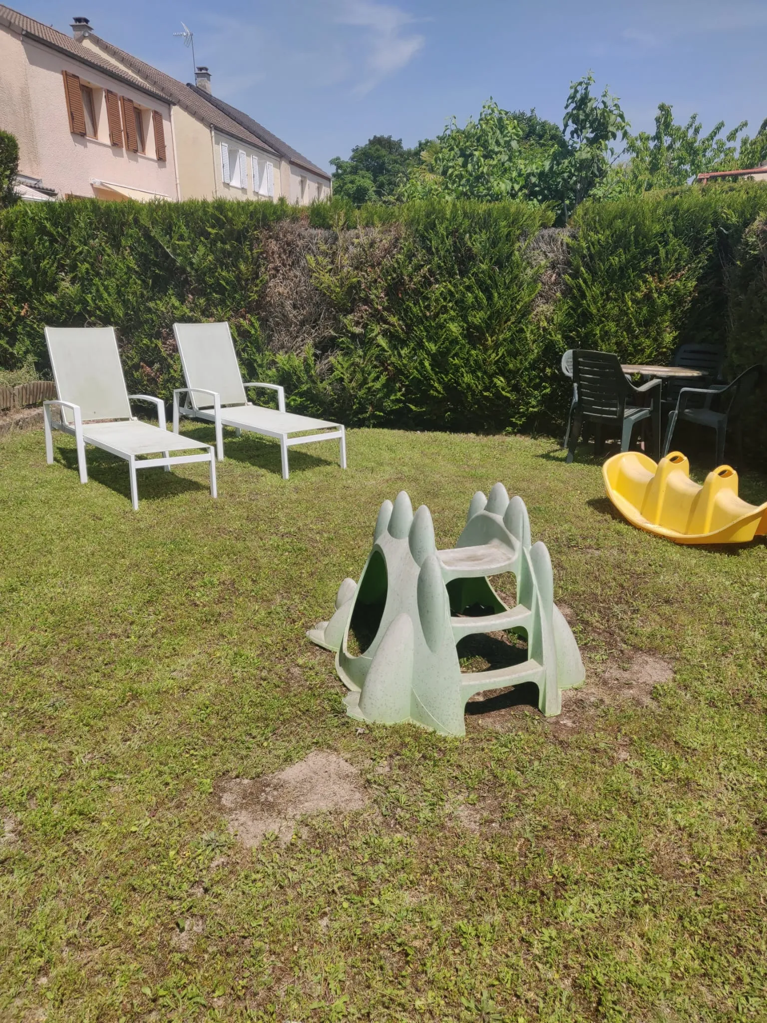 Jardin extérieur avec transats, toboggan et trébuchet à bascule.