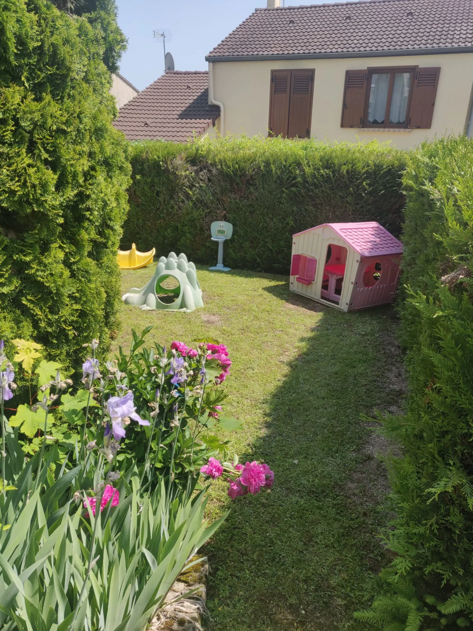 Jardin avec fleurs, maisonnette, trébuchet à bascule et panier de basket.