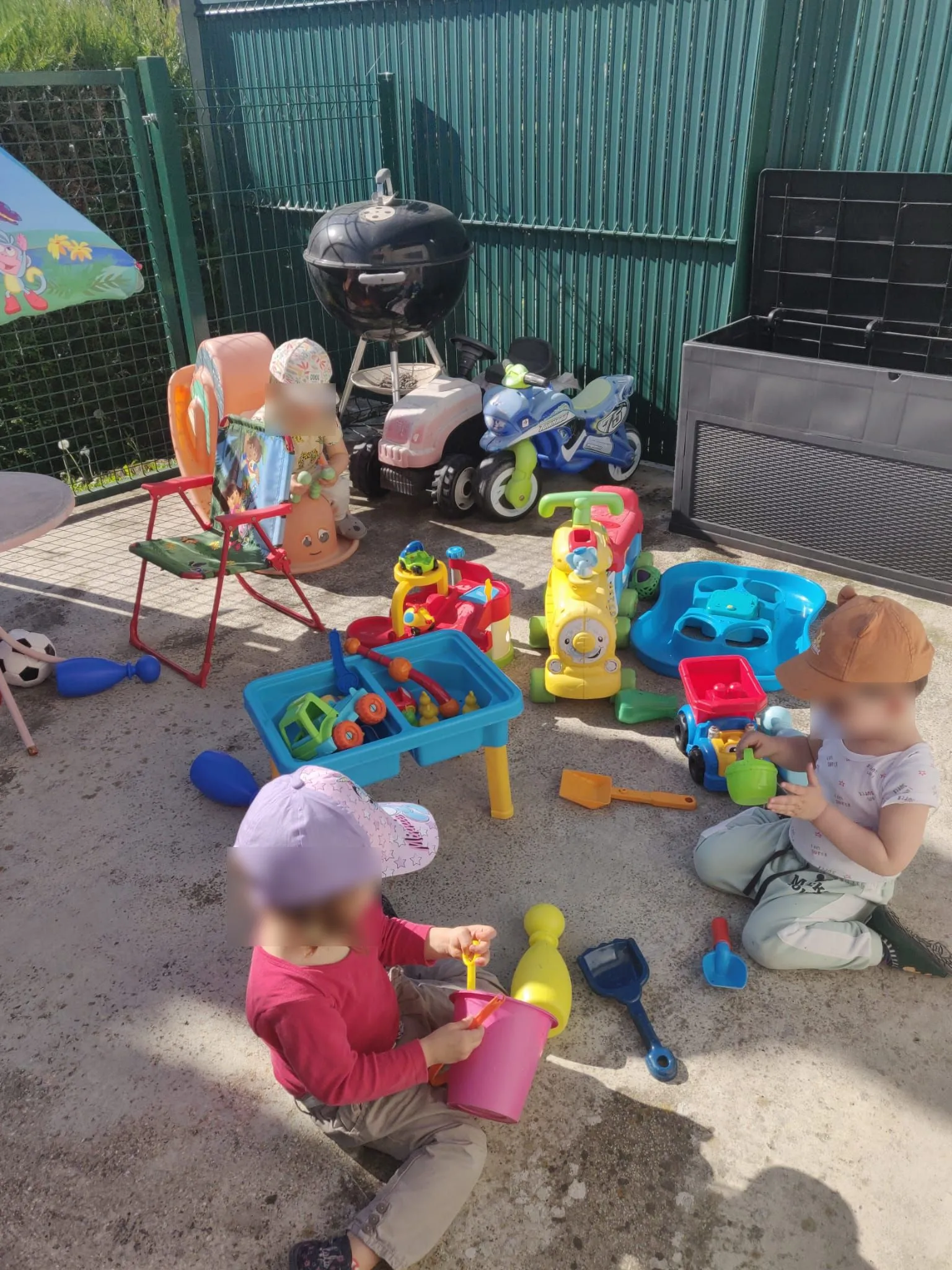 Trois enfants jouent avec des jouets sur la terrasse sécurisée.