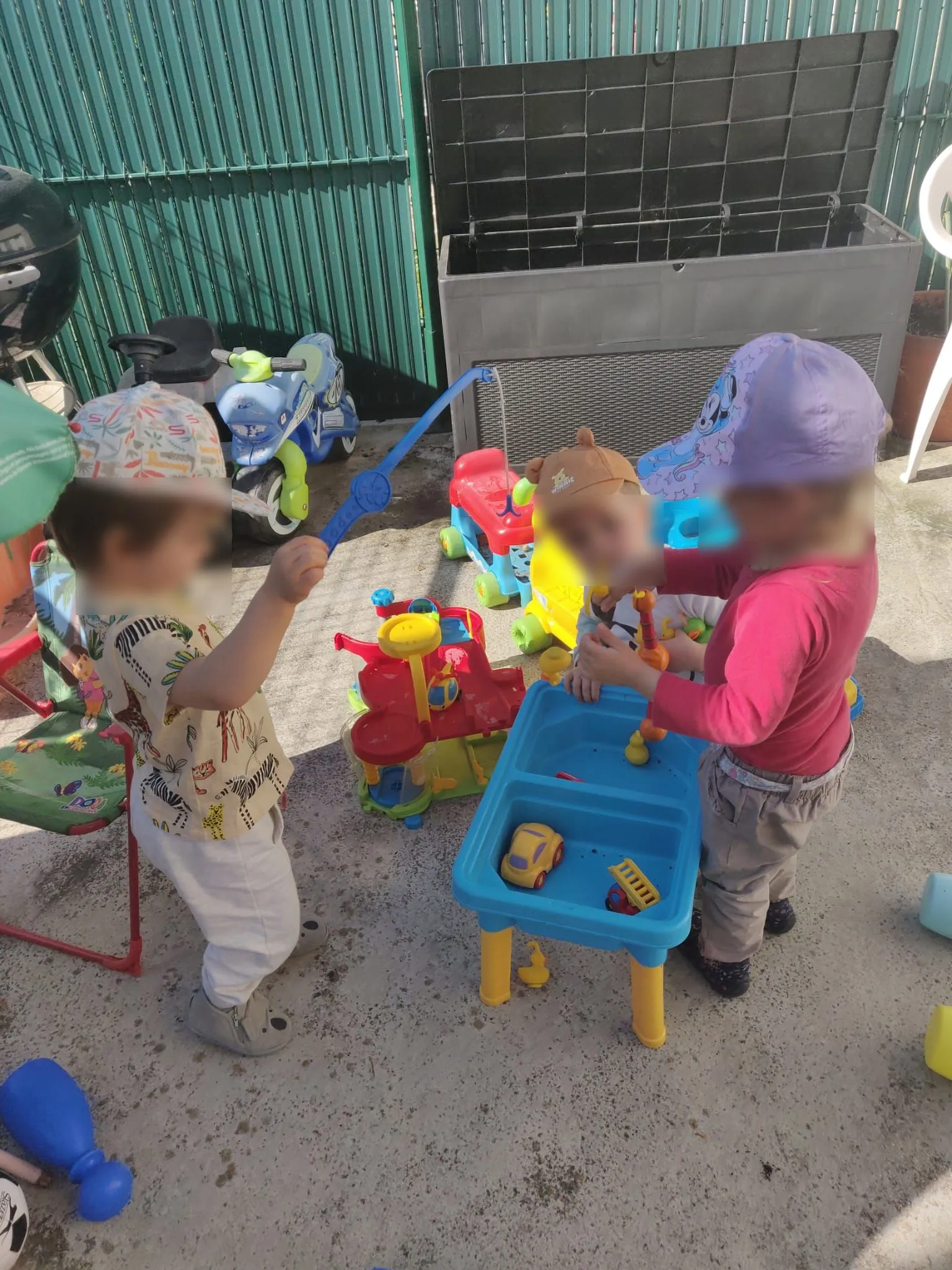 Trois enfants jouent avec des jouets sur la terrasse sécurisée.
