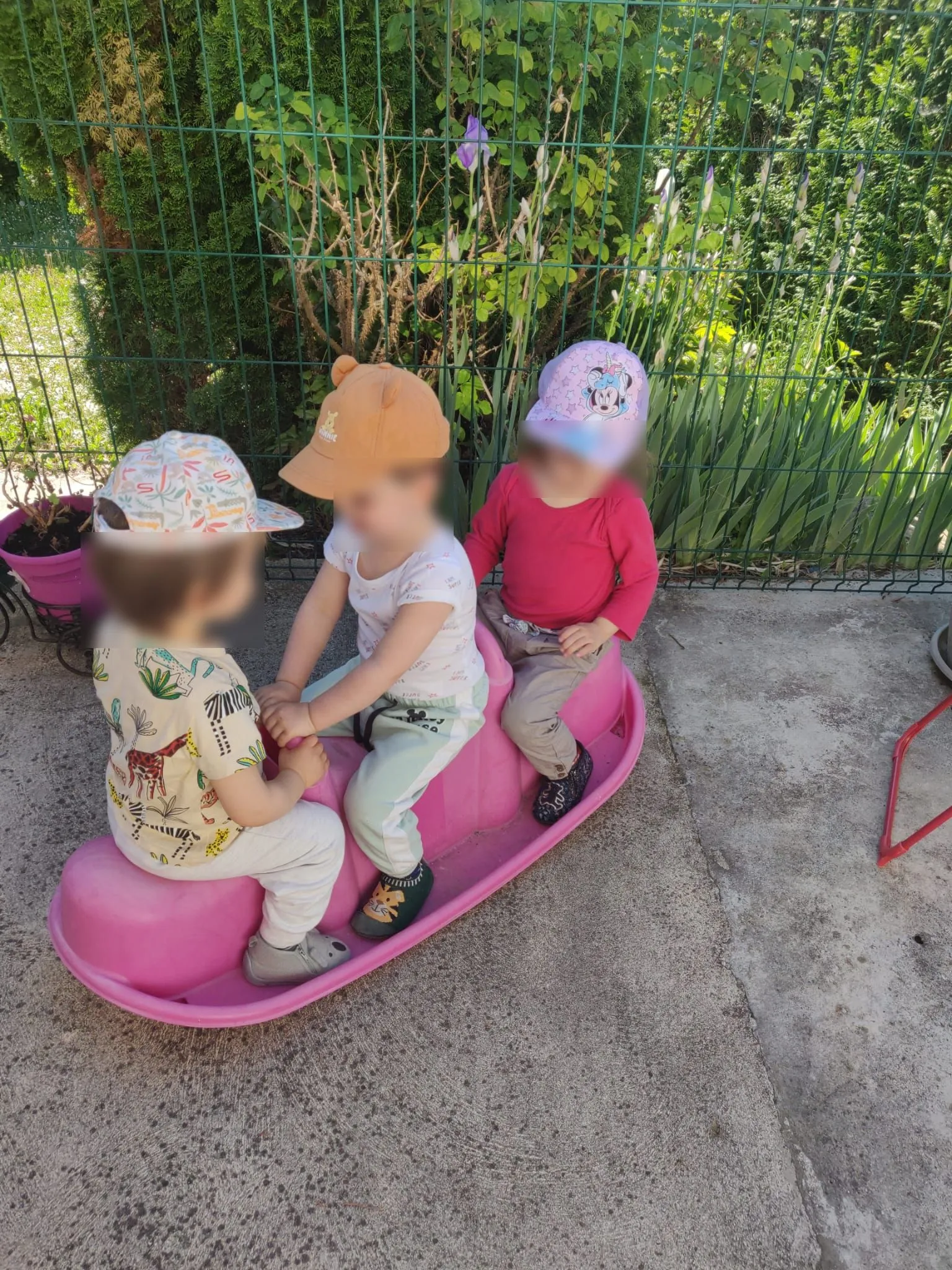 Trois enfants jouent sur un trébuchet à bascule sur la terrasse sécurisée.
